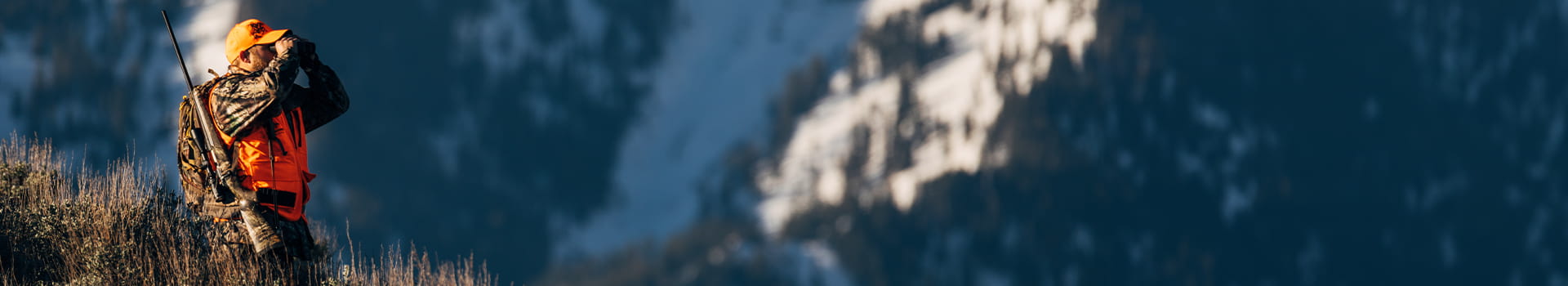 Man standing on mountain with XPR and binoculars